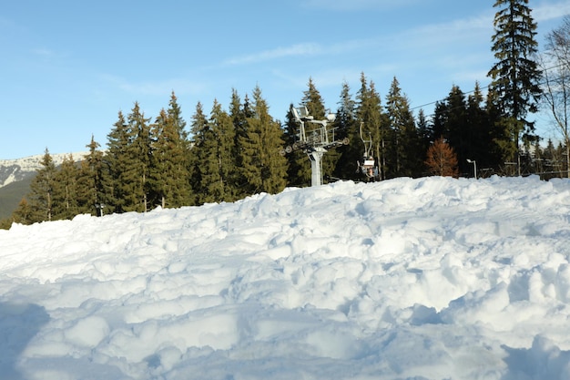 Neige contre remontées mécaniques, forêt et ciel bleu