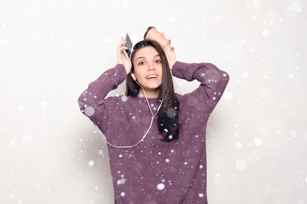 Neige, hiver, Noël, technologie, mode de vie, dépendance à Internet et concept de personnes - Belle jeune femme avec téléphone intelligent. femme séduisante souriante regardant le fond de neige de téléphone portable