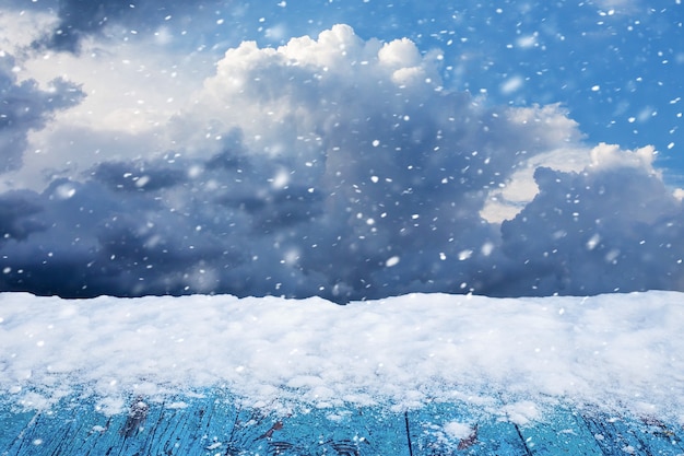 Neige sur une table en bois sur fond de ciel nuageux d'hiver lors d'une chute de neige