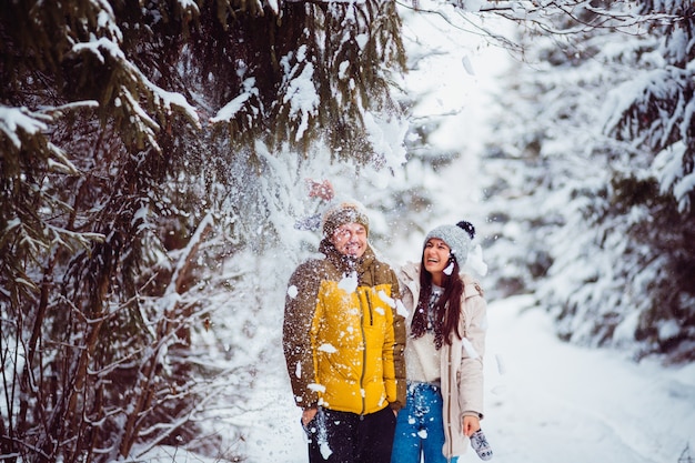 La neige tombe sur le beau couple debout dans la forêt d&#39;hiver