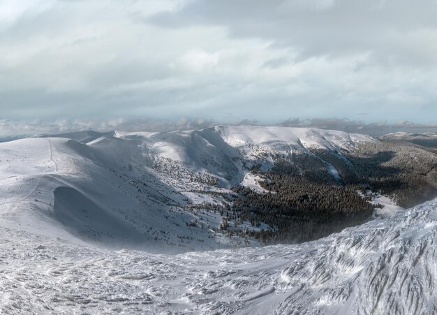 La neige et le vent ont formé des formations de glace couvertes d'hiver les sommets des plateaux de montagnes avec des corniches de neige au loin Magnifique jour ensoleillé sur une pittoresque belle crête alpine