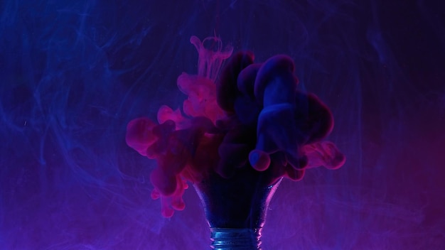 Néon fumée fond peinture eau mélange idée créative bleu rose couleur éclaboussure d'encre dans une ampoule cassée