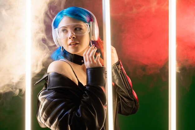 Neon light people Cyberpunk club Vague rétro Superbe mystérieuse femme futuriste dans un casque la nuit dans une lampe à LED lueur fumée sombre copie espace arrière-plan