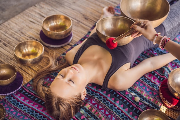 Népal bouddha bol chantant en cuivre au spa salon belle jeune femme faisant le chant de thérapie de massage