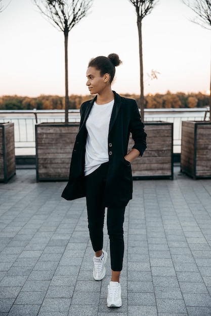 Énergie et heureuse jeune femme afro-américaine lève les jambes et saute