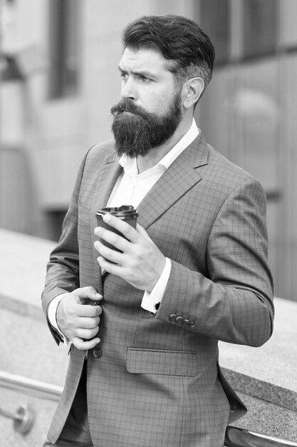 Énergie de la marque Directeur exécutif masculin confiant avec du café à emporter Homme prospère propriétaire d'entreprise a une pause-café beau mec porte une veste de bureau chère gaieté du matin avec du café