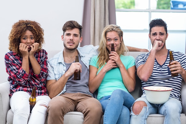 Nerveux amis multiethniques regardant la télévision à la maison