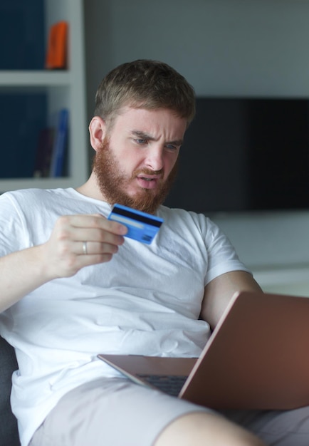 Nerveux triste bouleversé confus jeune homme stressé gars inquiet ayant des problèmes avec le paiement de l'achat en ligne