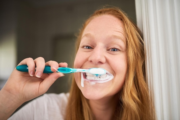 Nettoyage complet lorsque je me brosse les dents Photo d'une jeune femme se brossant les dents à la maison