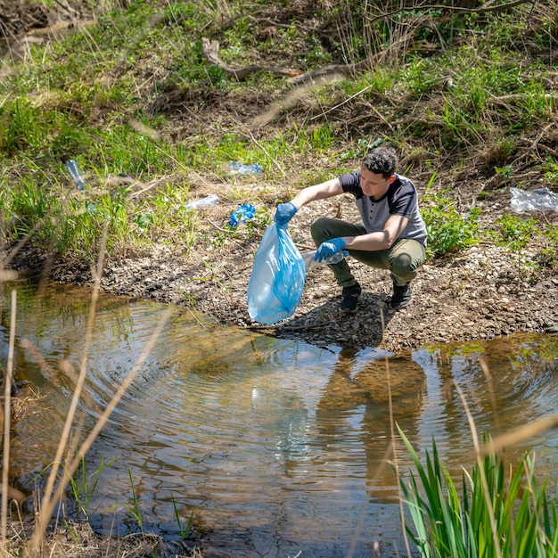 Photo nettoyage des déchets plastiques sur la rive du fleuve par un volontaire. aider la nature et protéger l'environnement