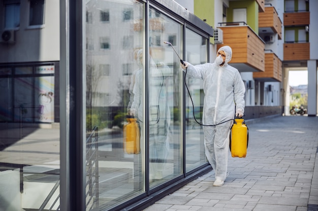 Photo nettoyage et désinfection à l'extérieur autour des bâtiments, l'épidémie de covid-19. équipes de session pour les efforts de désinfection. prévention des infections et contrôle de l'épidémie. costume et masque.