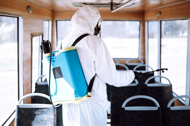 Nettoyage et désinfection des transports en commun. Homme en tenue de protection lavant et désinfectant les transports publics.