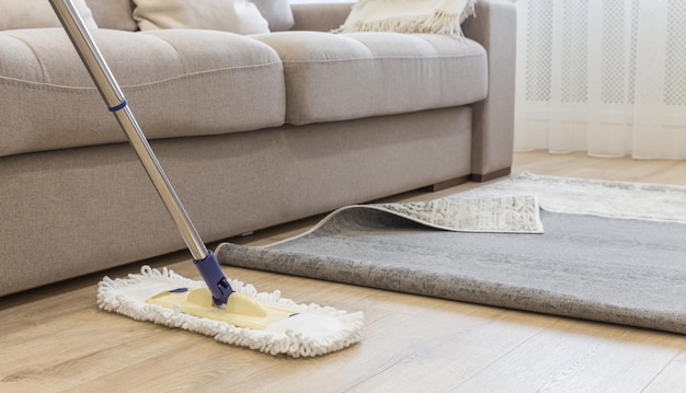 Nettoyage du sol avec vadrouille sous tapis dans le salon