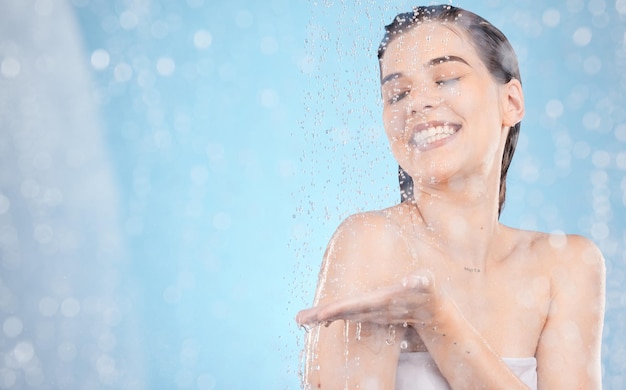 Nettoyage à l'eau et maquette avec une femme sous la douche en studio sur fond bleu pour l'hygiène ou l'hydratation Soins de santé et vapeur avec une jolie jeune femme se lavant dans la salle de bain