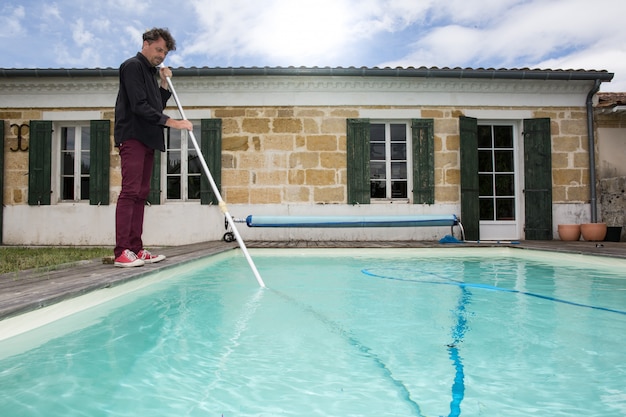 Nettoyage homme bleu piscine avec aspirateur