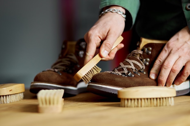 Nettoyage de la main de l'homme chaussures en daim avec une brosse sur plancher en bois