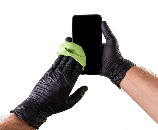 Nettoyage à la main d'un smartphone avec des gants noirs. Empêcher le nettoyage domestique