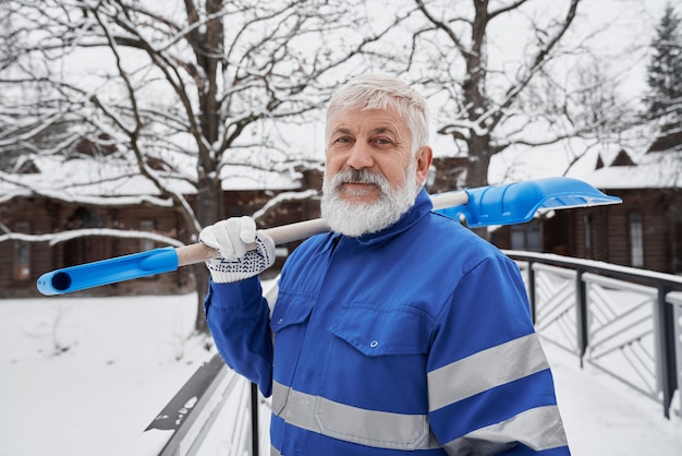 Nettoyant en salopette de travail avec pelle pour enlever la neige.