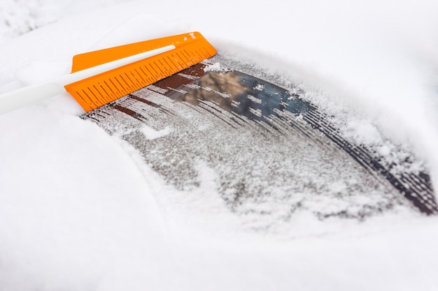 Nettoyer la neige de la voiture avec une brosse