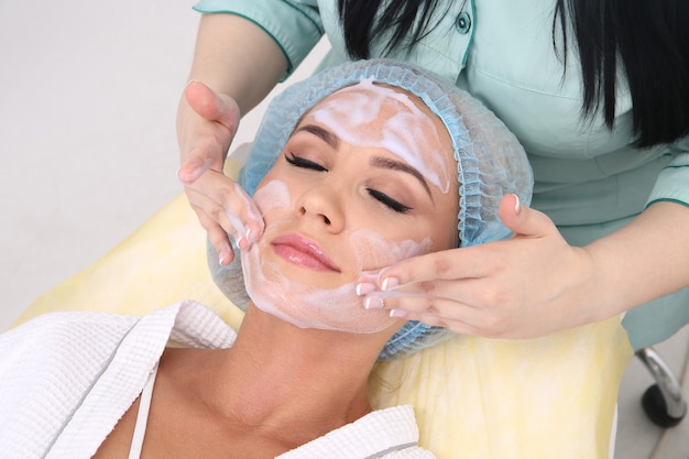 Nettoyer la peau avec de la mousse, une belle femme dans la beauté du salon de beauté