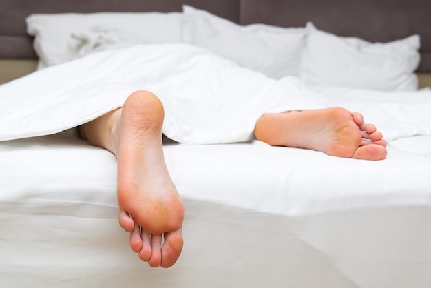 Nettoyer les pieds adultes au lit avec du linge blanc