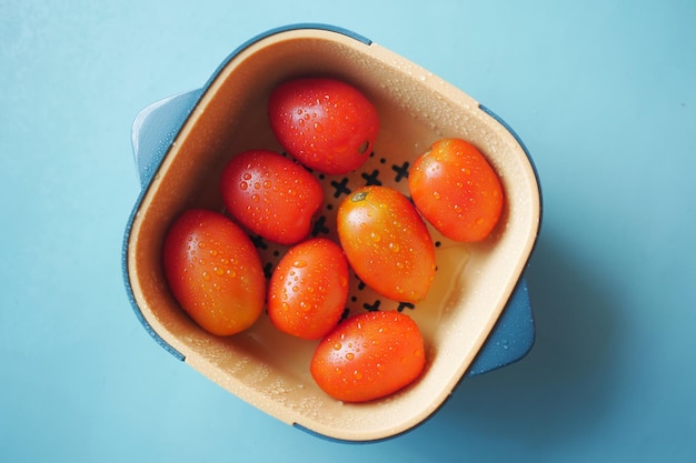 Nettoyer la tomate fraîche avec de l'eau dans un bol en plastique