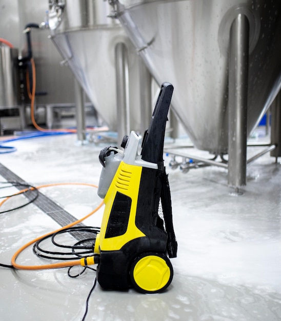 Un nettoyeur à haute pression de couleur noire et jaune posé sur le sol dans l'entrepôt