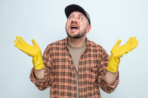 Un nettoyeur slave impressionné avec des gants en caoutchouc gardant les mains ouvertes et levant les yeux