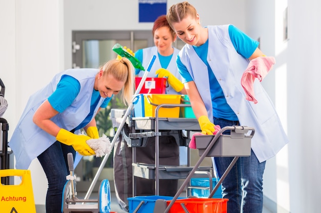 Les nettoyeurs commerciaux font le travail ensemble, trois femmes avec chariot travaillant