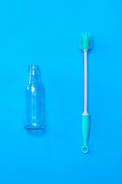 Nettoyez la bouteille en verre et lavez la brosse sur la surface bleue. Le concept d'hygiène et de propreté.