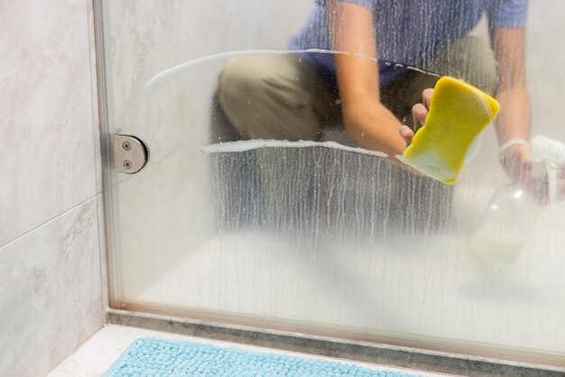 Photo nettoyez le verre des fenêtres de la salle de bain avec une éponge