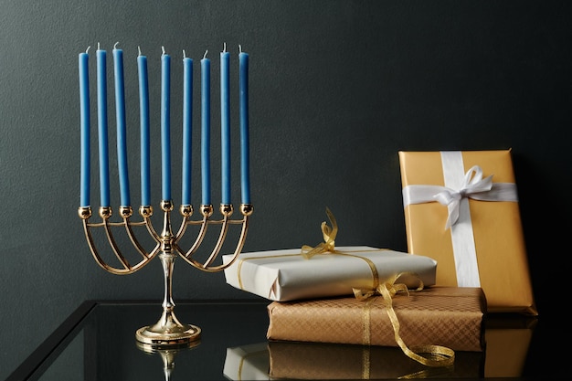 Photo neuf menorah de bougies bleues debout sur la table à côté d'un tas de cadeaux emballés