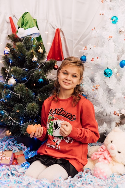 New Yeargirl dans une salle de jour tenant une tasse et des mandarines