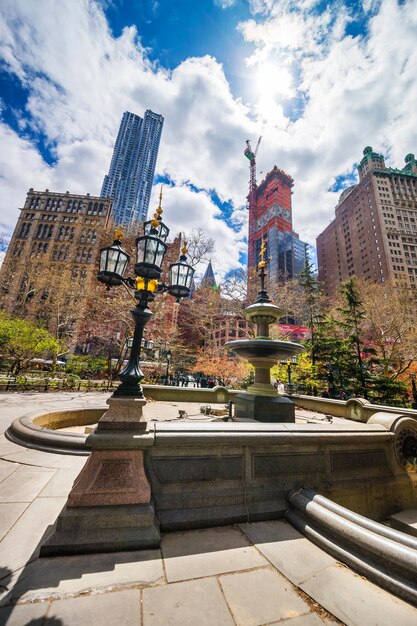 New York, États-Unis - 24 avril 2015 : Lanterne de rue et fontaine dans le parc de l'hôtel de ville dans le Lower Manhattan, New York, New York, États-Unis. Gratte-ciels et touristes en arrière-plan.