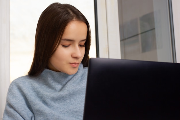 Nice European girl at home sitting at a laptop, working, shopping