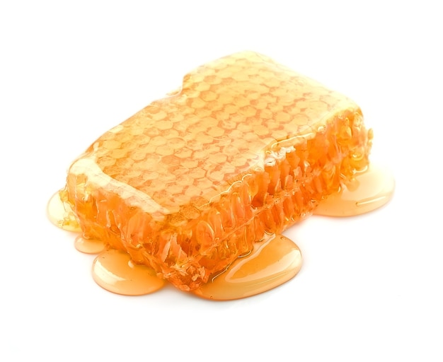 Nid d'abeille avec du miel liquide isolé sur blanc