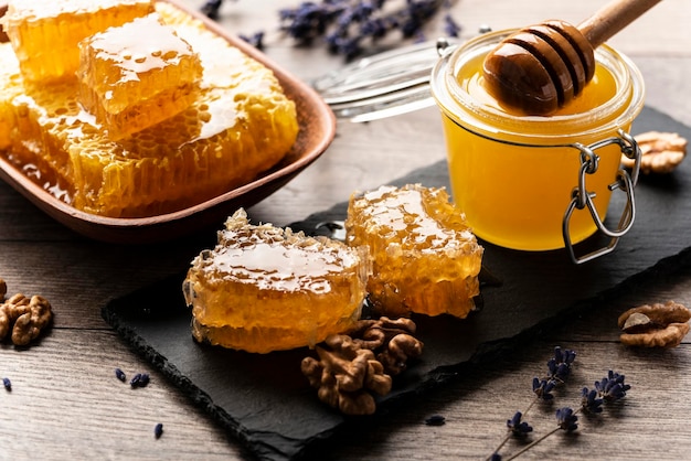 Nid d'abeille sur plateau en ardoise avec du miel et des noix sur la table de la cuisine