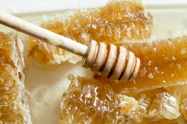 Nid d'abeille scellé avec louche à miel en bois pour mélanger et goûter le miel naturel