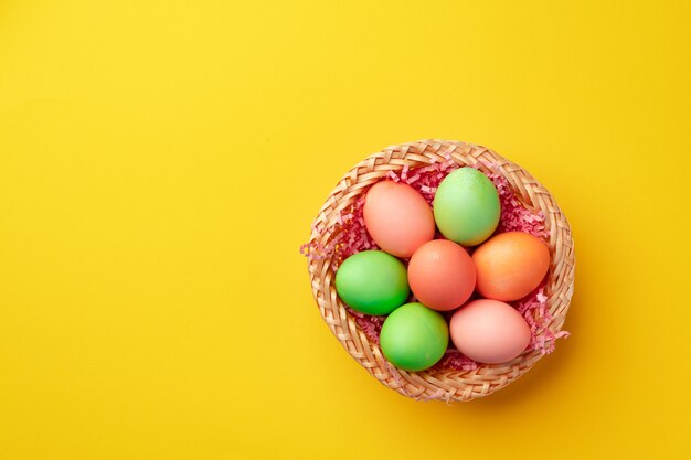 Nid décoratif avec des oeufs de Pâques colorés sur jaune close up