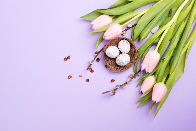 Nid avec petits oeufs et tulipes roses sur fond violet, carte de voeux de vacances de pâques