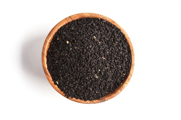 Nigella sativa ou cumin noir dans un bol en bois sur fond blanc, espace copie, vue de dessus, isoler