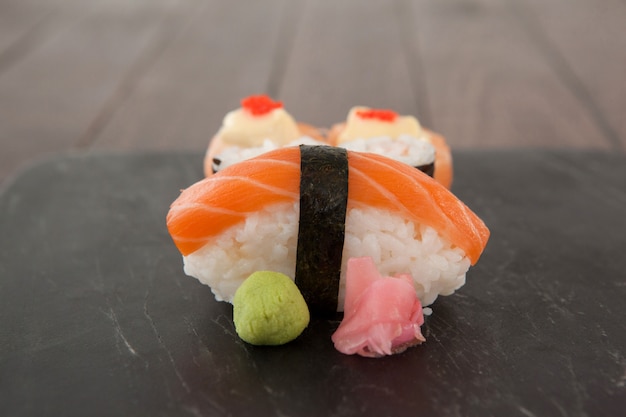 Nigiri et sushi uramaki servi sur ardoise en pierre noire sur table en bois