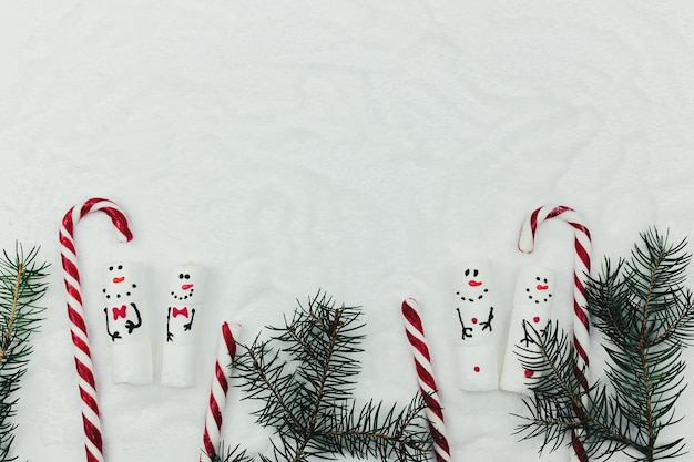 Noël avec bonhomme de guimauve sur la fausse neige avec sapin et sucette.