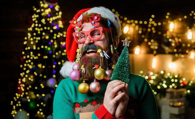 Noël célébration du Nouvel An homme heureux dans le chapeau de Père Noël avec des boules de Noël dans la barbe avec petit