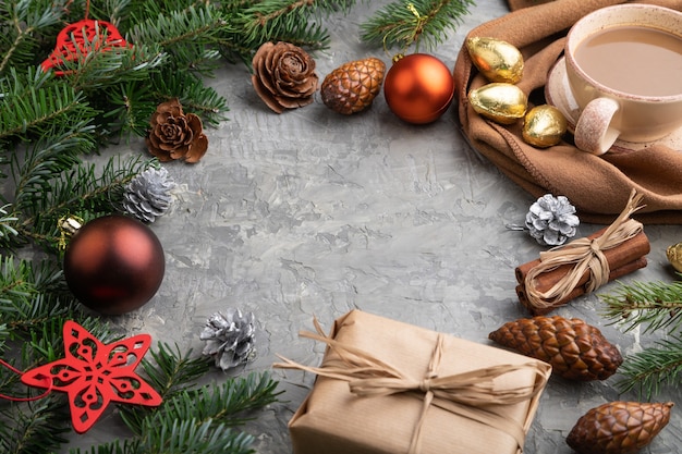 Noël ou composition. Décorations, cônes, branches de cannelle, sapin et épicéa, tasse de café, écharpe en laine sur béton gris.