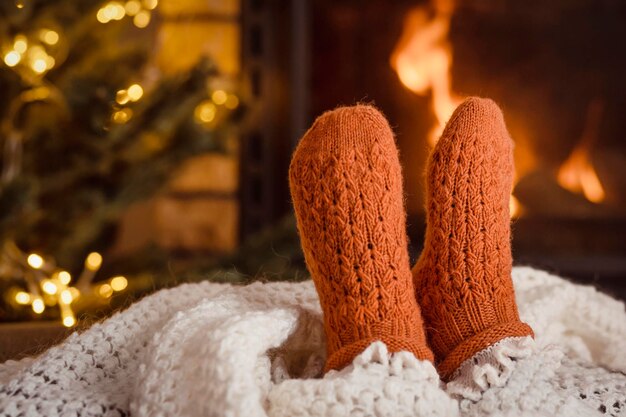 Photo noël détente vacances jambes de fille dans des chaussettes tricotées en laine sur le feu de cheminée arrière-plan à la maison confortable