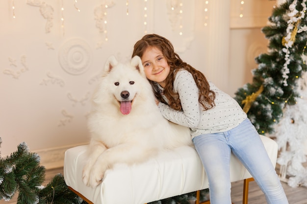 Noël enfant fille câlin chien Samoyède à la maison