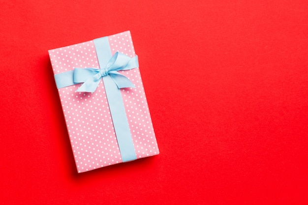 Noël enveloppé ou autres vacances à la main présent en papier avec ruban bleu sur fond rouge