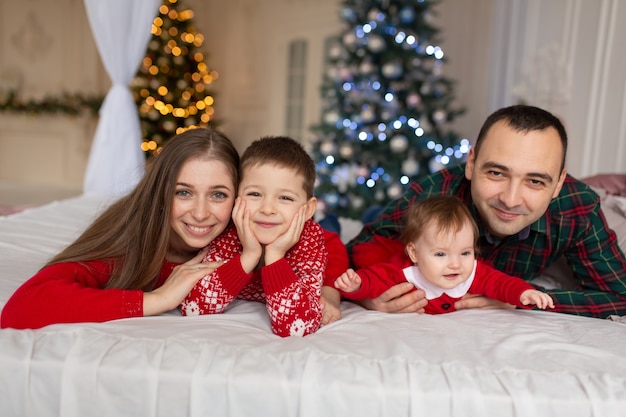 Noël en famille! Heureuse maman, papa et petite fille et fils, couchés. gens de vacances