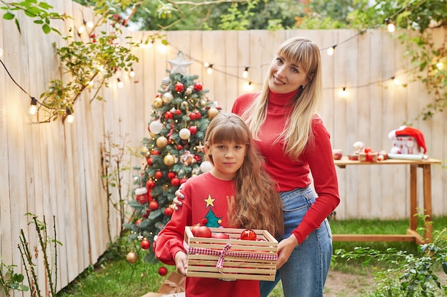 Noël en famille en juillet Portrait de jeune fille près de l'arbre de Noël avec des cadeaux Décoration de pin Hiver